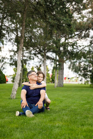 Full length image of a niece hugs her grandfather in the park on a sunny day. Outdoor portrait.の写真素材