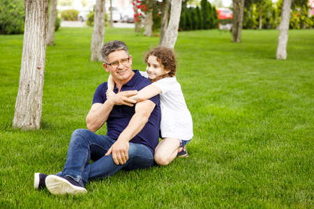 Full length image of a niece hugs her grandfather in the park on a sunny day.の写真素材