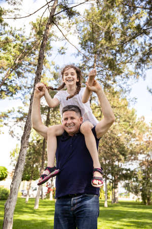 Grandfather holds his niece on his shoulders, he enjoys of a good day together in nature.の写真素材