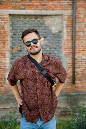Closeup front portrait of a young hipster man in sunglasses stand near building wall outdoors.の写真素材
