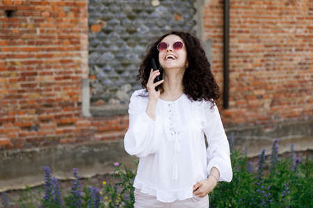 Pretty young woman close-up in orange sweater talking on cell phone. outdoor portrait.の写真素材