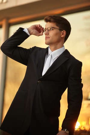 Handsome businessman posing in eyeglasses and black suit, wear watch on his hand.の写真素材
