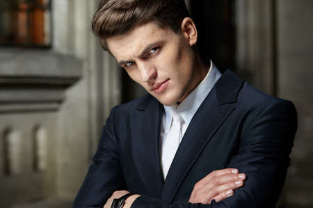 Portrait of a handsome businessman posing with crossed arms in black suit, wear watch on his hand.の写真素材