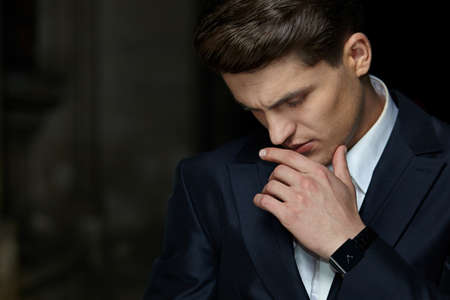 Close-up portrait of a confident businessman posing in black suit, wear watch on his hand, isolated black background.の写真素材