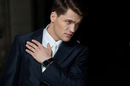 Confident businessman posing in black suit, wear watch on his hand.の写真素材