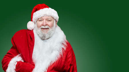 Closeup image of a happy Santa Claus dressed in a red coat and a hat, keep a bag on his back,...