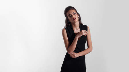 Frontal beauty portrait of a young woman with makeup, red lipstick, dressed in black dress, isolated white background.の写真素材