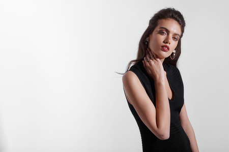 Beauty portrait of a brunette young woman with makeup, red lipstick, dressed in black dress, isolated white background.の写真素材