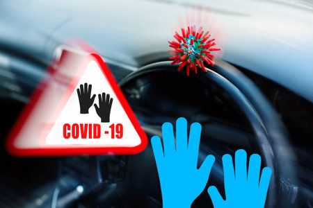 Headline with inscription COVID-19 and blue gloves, with virus strain sitting on the door of vehicle.の写真素材