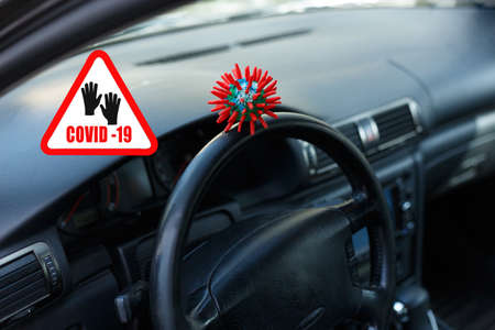 Abstract virus COVID-19 strain model sitting on the steering wheel of a vehicle and human hand in medical gloves.の写真素材