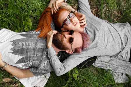 Top view of a couple, seated down on a green grass with turned heads with closed eyes. Couple relationship.の写真素材