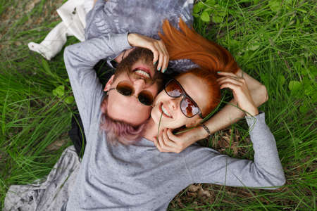 Top smiling people in a sunglasses, seated down on a green grass, looking at camera.の写真素材