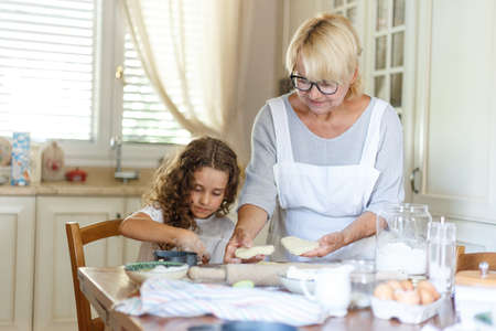 A grandmother and niece is cooking. A cheerful grandmother is cooking a cookies.の写真素材