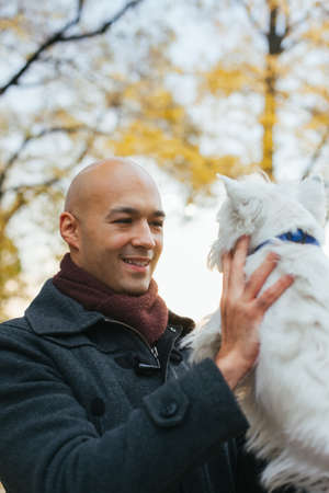 Man holding a West Highland White Terrier on sunsetの写真素材