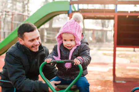 Happy dad and daughter having fun at playgroundの写真素材