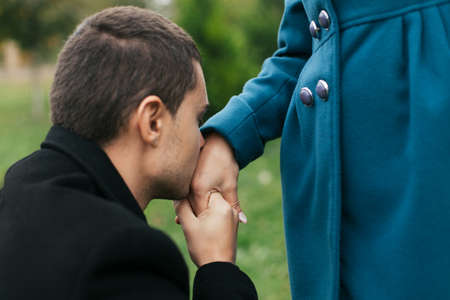 Man kneeling and kissing womans hand. Outdoorsの写真素材