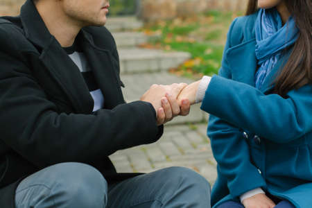 Man and woman sitting on stairs. Man holding woman's handの写真素材