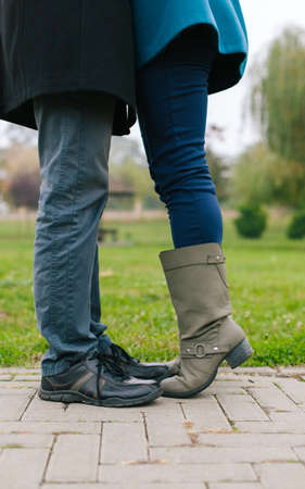 Couple kissing outdoors. Lovers on a romantic date, girl stands on tiptoe to kiss her man. Close up on shoesの写真素材