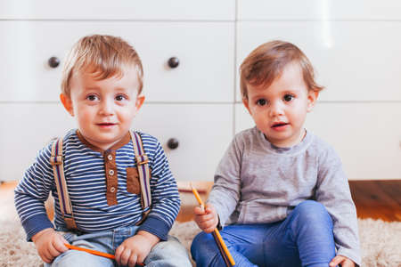 Happy little children sitting on the floor and painting indoorsの写真素材