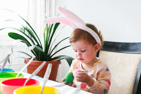Easter concept. Portrait of little girl holding colored Easter eggの写真素材