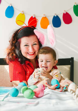 Easter concept. Grandmother and happy little girl holding eggs and smilingの写真素材