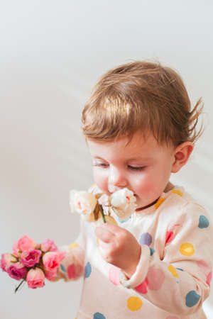 Portrait of beautiful little girl smelling flowers with copy spaceの写真素材