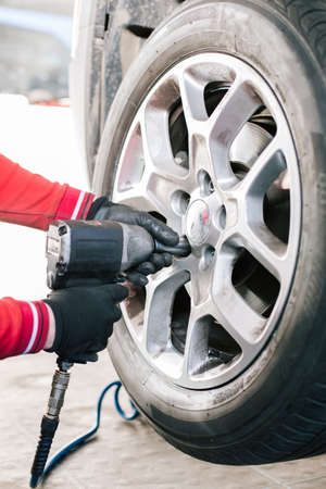 Mechanician changing car wheel in auto repair shop closeupの写真素材
