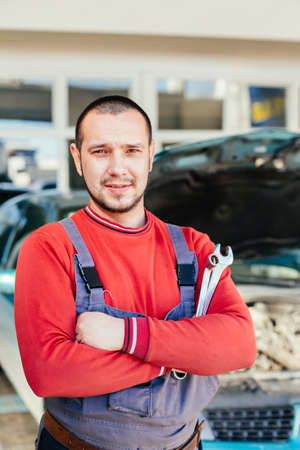 Portrait of a mechanic standing in front of car in auto service garageの写真素材
