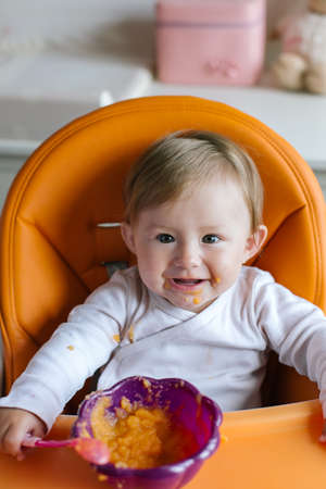 Portrait of smiling baby girl In high chairの写真素材