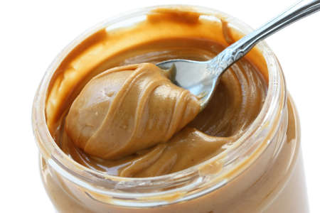 an open jar of peanut butter with spoonの写真素材