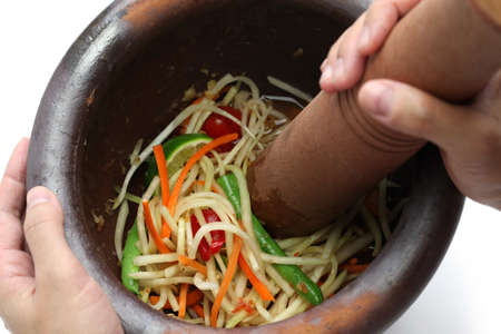 making of green papaya salad, som tam, thai food, ingredients are mixing and pounding in a mortar  の写真素材