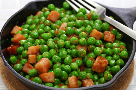 fresh green peas with ham in skilletの写真素材