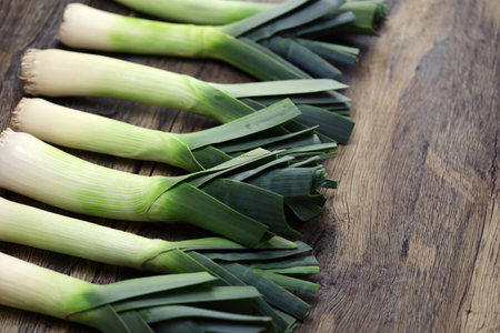 freshly harvested leeks isolated on wooden background. copy space