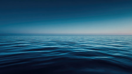 A serene seascape captures the essence of tranquility. The calm water surface reflects gentle waves against a backdrop of fading blue sky at dusk.の素材