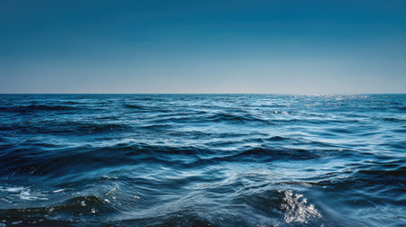 This scenic image captures the vastness of the ocean under a clear blue sky, showcasing gentle waves and shimmering sunlight reflections, perfect for evoking a sense of tranquility and adventure.の素材