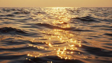A stunning view of calm ocean waves glistening with golden reflections from the setting sun. The image captures the serene beauty of the water's surface.の素材