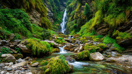 A breathtaking view of a majestic waterfall pouring into a crystal-clear stream amidst a vibrant green mountainous terrain, creating a peaceful oasis.の素材