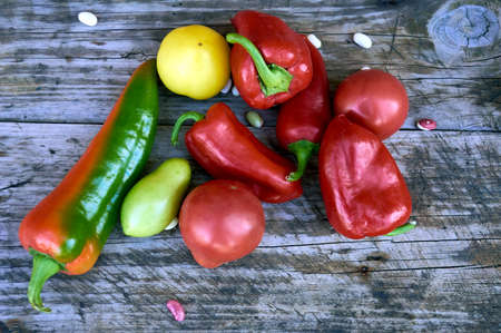 tomatoes, peppers and beans are lying on an old wooden tableの写真素材