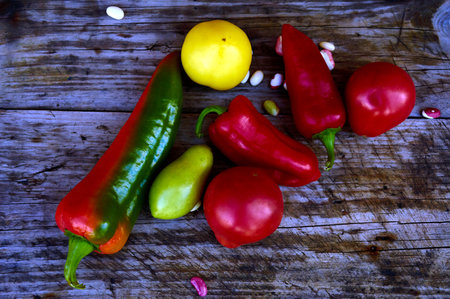 tomatoes, peppers and beans are lying on an old wooden tableの写真素材