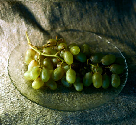 a bunch of grapes on a glass dish on a background of burlapの写真素材