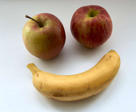ripe red apples and banana on a white background in natural lightの写真素材