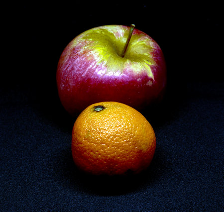 red apple and tangerine on an ominous black backgroundの写真素材