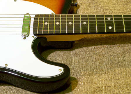 the electric guitar is lying on a piece of burlap