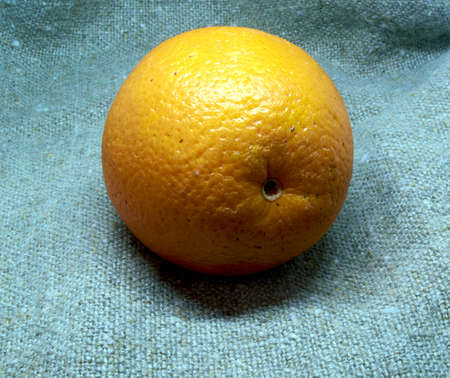 an orange from Africa is lying on a rag bagの写真素材