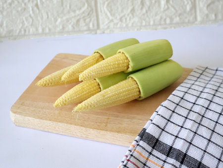 Baby corn on a cutting board with a checkered napkinの写真素材