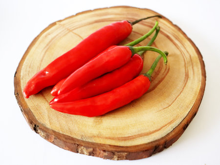 Fresh looking red big chilies on a wooden chopの写真素材