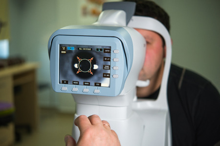 The ophthalmologist conducts the research with the help of various equipment, a contactless tonometer, for the diagnosis of eye diseaseの写真素材