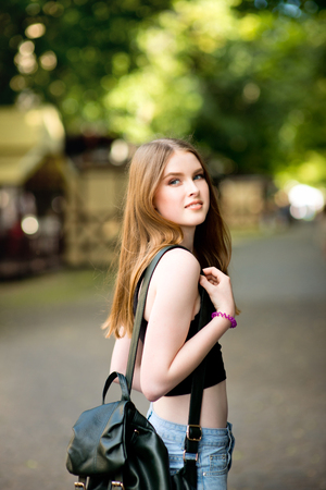 Young beautiful stylishly dressed girl is walking along the streets of the city, talking on mobile phoneの写真素材