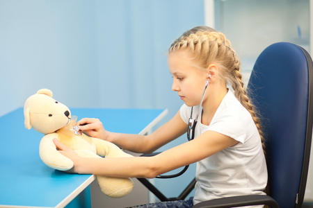 The girl with a soft toy in the hospital on a background of ultrasound machines, smiling and playingの写真素材