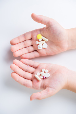 Tablets and pills in the hands of a close-up on a white backgroundの写真素材